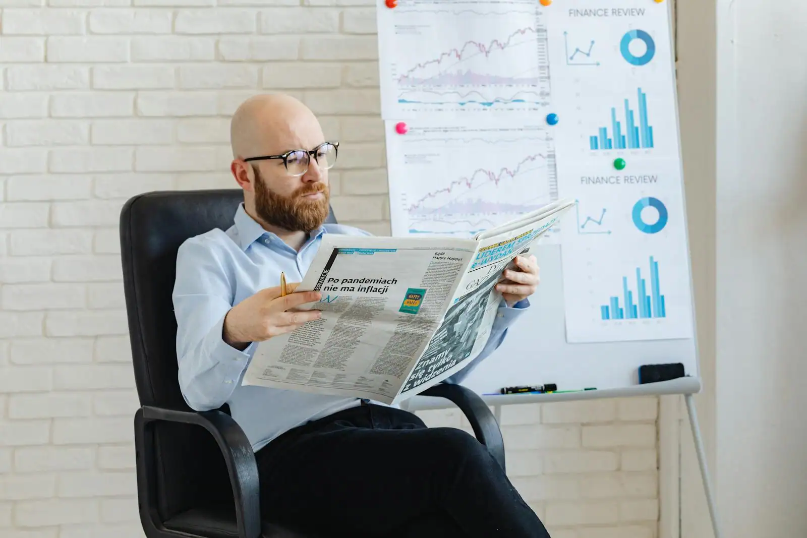 Page économie d'un journal financier posée sur un bureau à côté d'une tasse de café