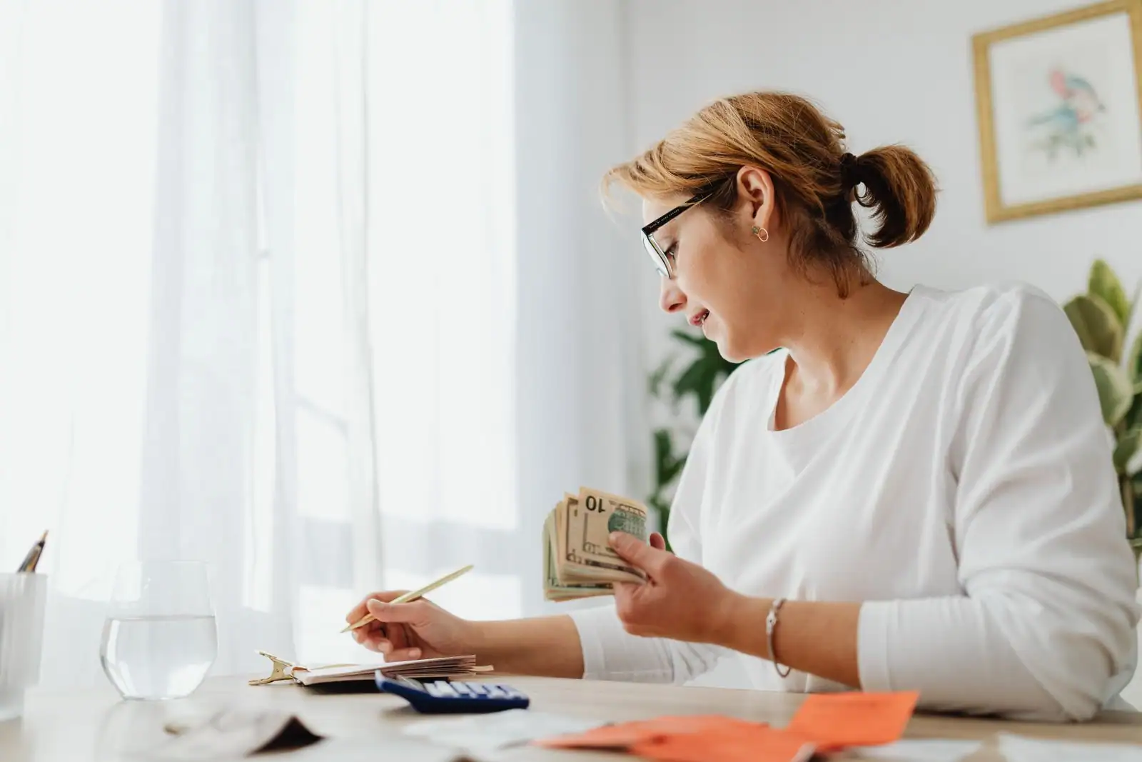 Personne comptant des billets avec une calculatrice et un carnet, illustrant la gestion financière en micro-entreprise.
