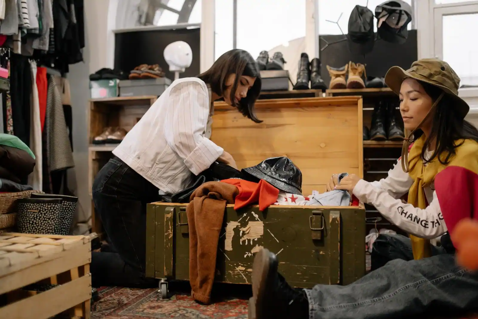Deux femmes trient des vêtements d’occasion dans une boutique de seconde main remplie d’articles.