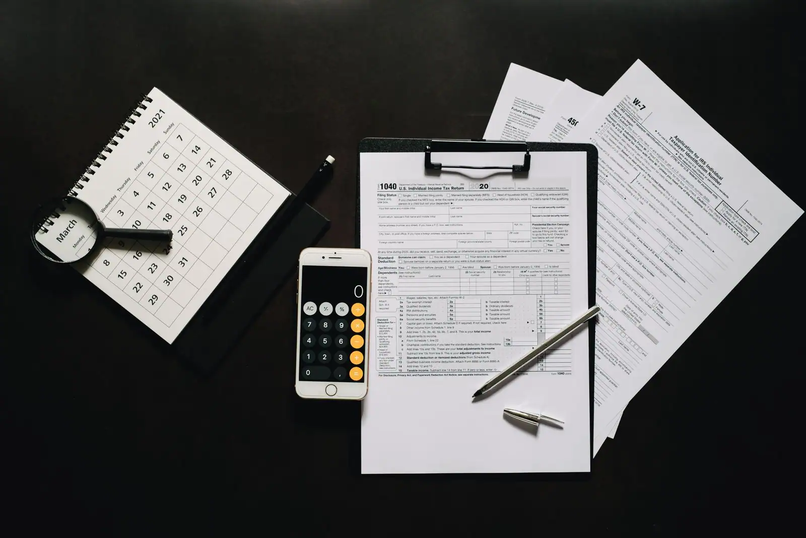 Formulaire de déclaration de revenus, calculatrice et stylo sur un bureau pour estimer son impôt.