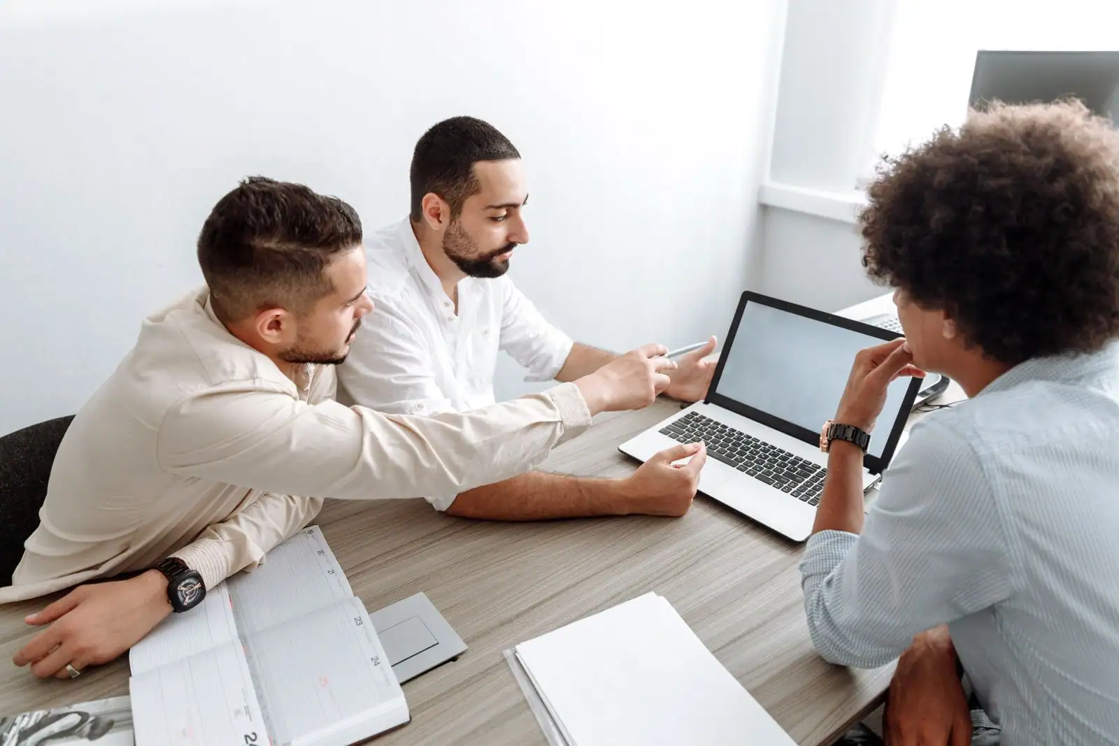 Équipe échangeant autour d'une table dans un bureau, illustrant la communication au sein d'une entreprise.