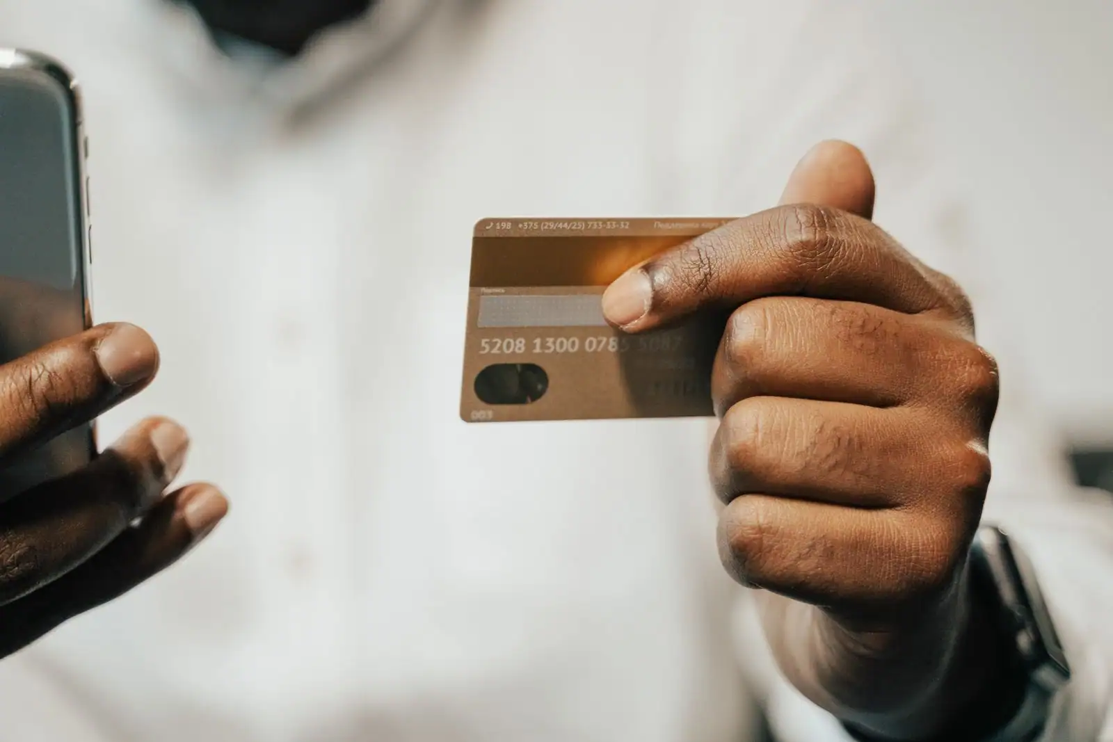 Personne tenant une carte bancaire et un smartphone, illustrant la gestion d'un compte au quotidien.