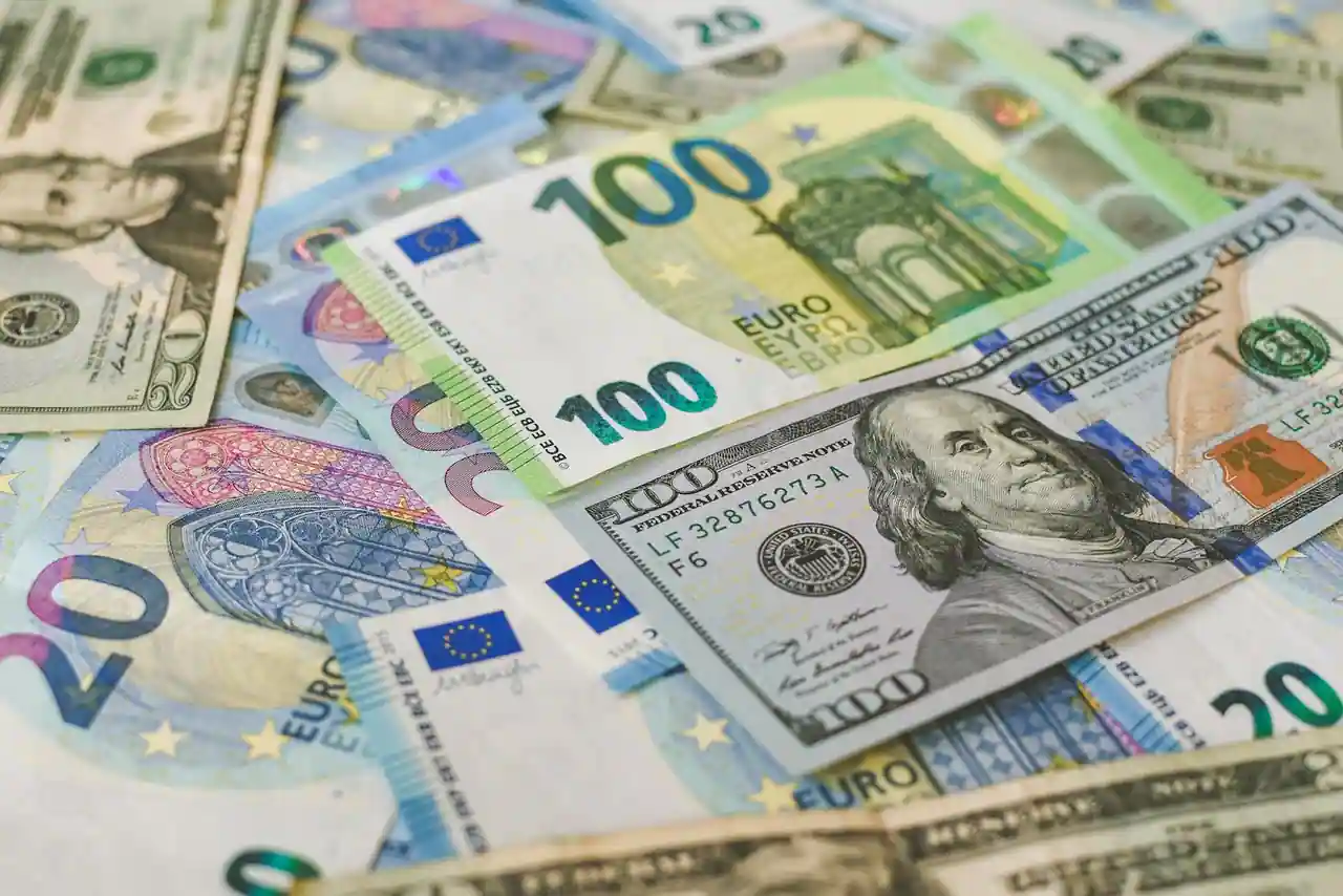 Billets en dollars et en euros côte à côte, illustrant la conversion entre les deux devises.