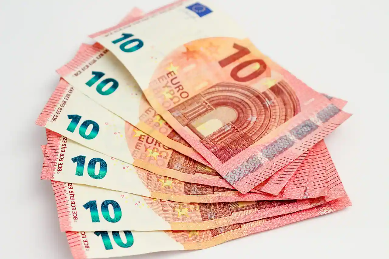 Éventail de billets de dix euros sur fond blanc, illustrant la monnaie européenne et le change de devises.