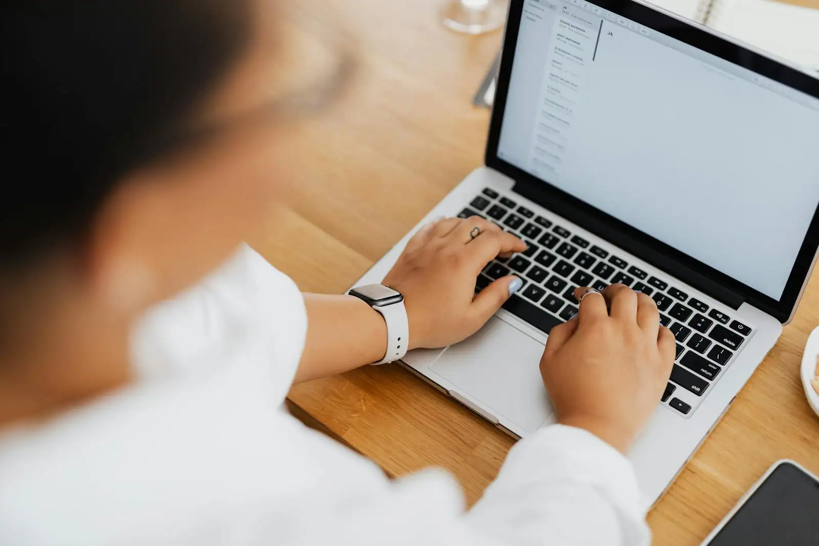 Personne remplissant un formulaire d'inscription à une messagerie sur l'écran d'un ordinateur portable posé sur un bureau.