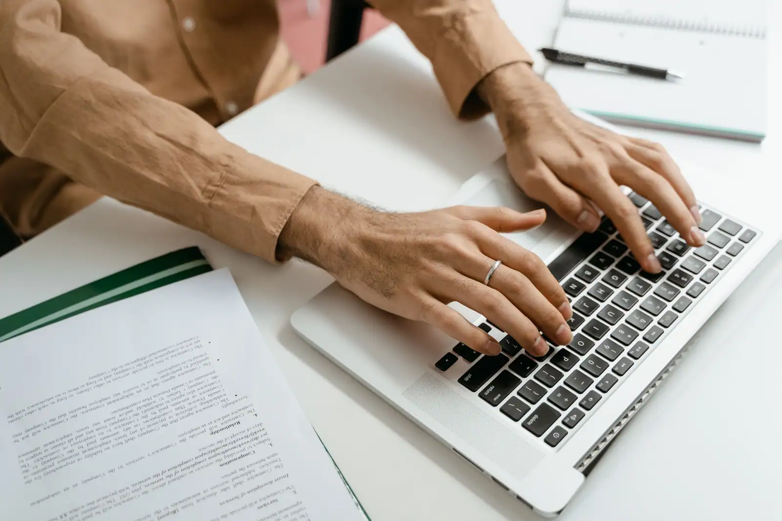 Une personne saisit ses informations sur un ordinateur portable, des documents posés sur le bureau.