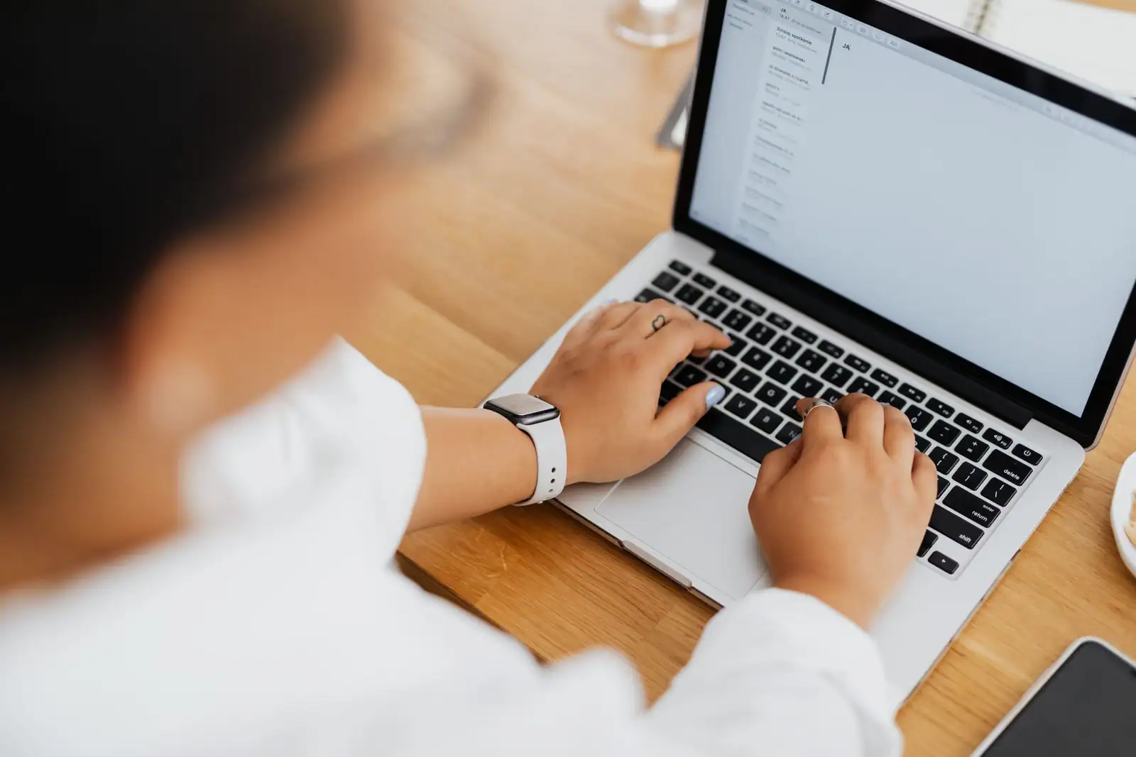 Personne tapant sur le clavier d'un ordinateur portable affichant une interface de messagerie