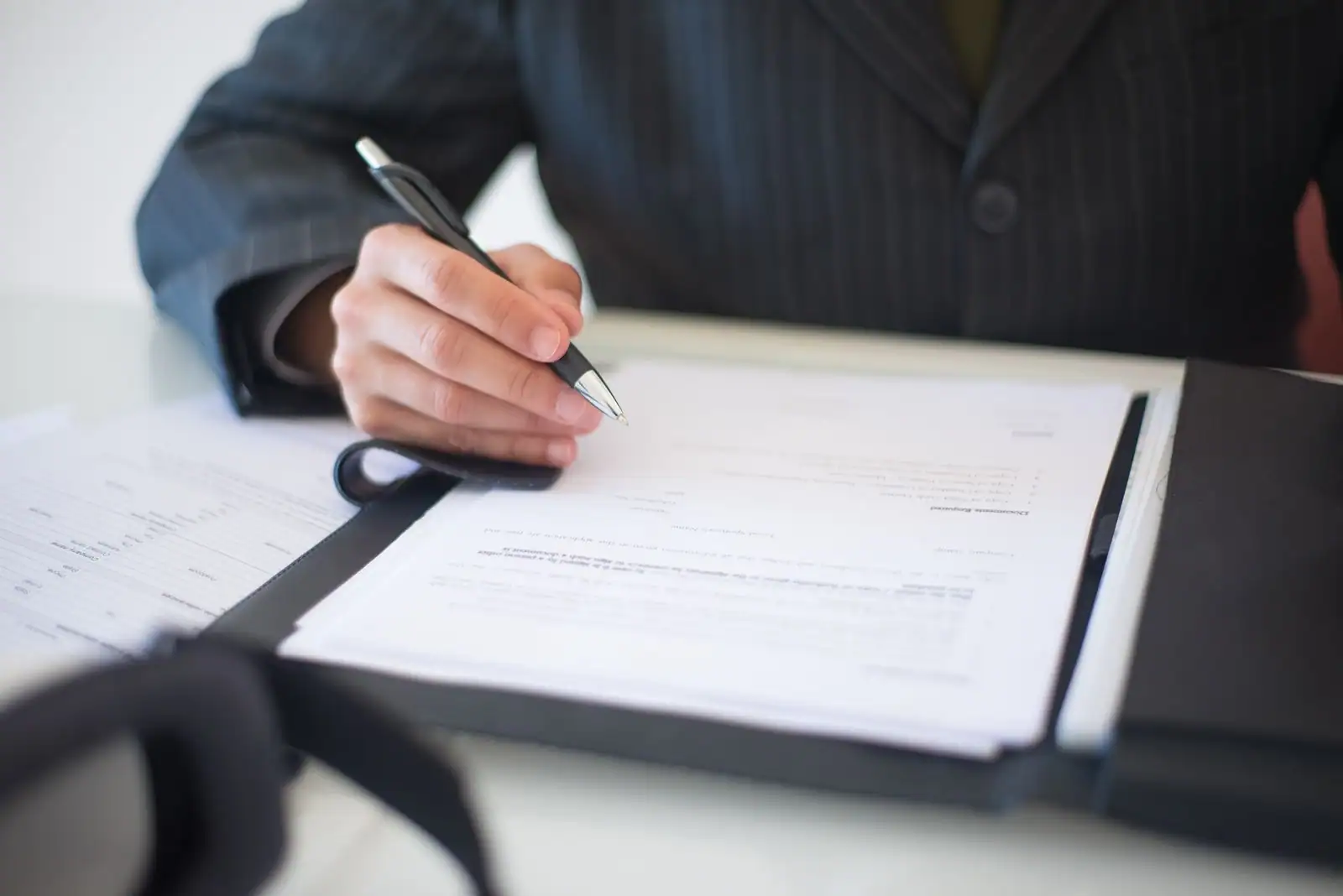 Personne en costume signant des documents administratifs à un bureau
