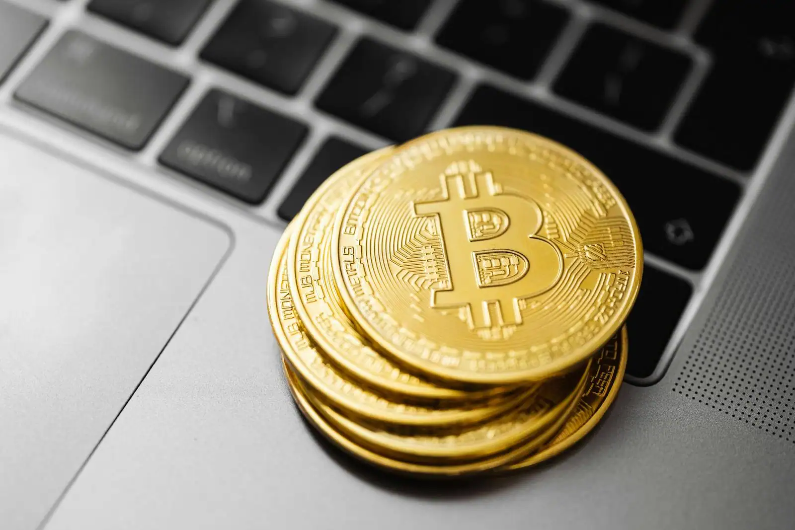 Des pièces dorées à l'effigie du bitcoin empilées sur un clavier d'ordinateur portable