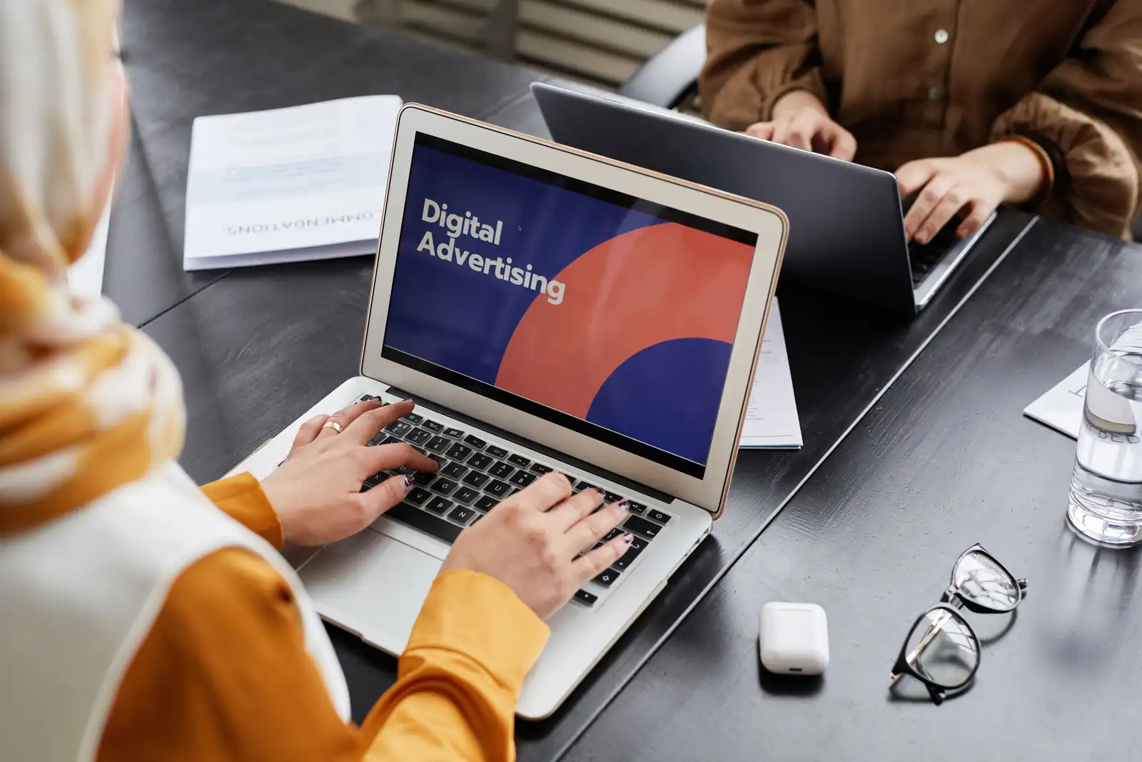 Deux professionnels travaillent sur des ordinateurs portables lors d'une session de marketing digital.