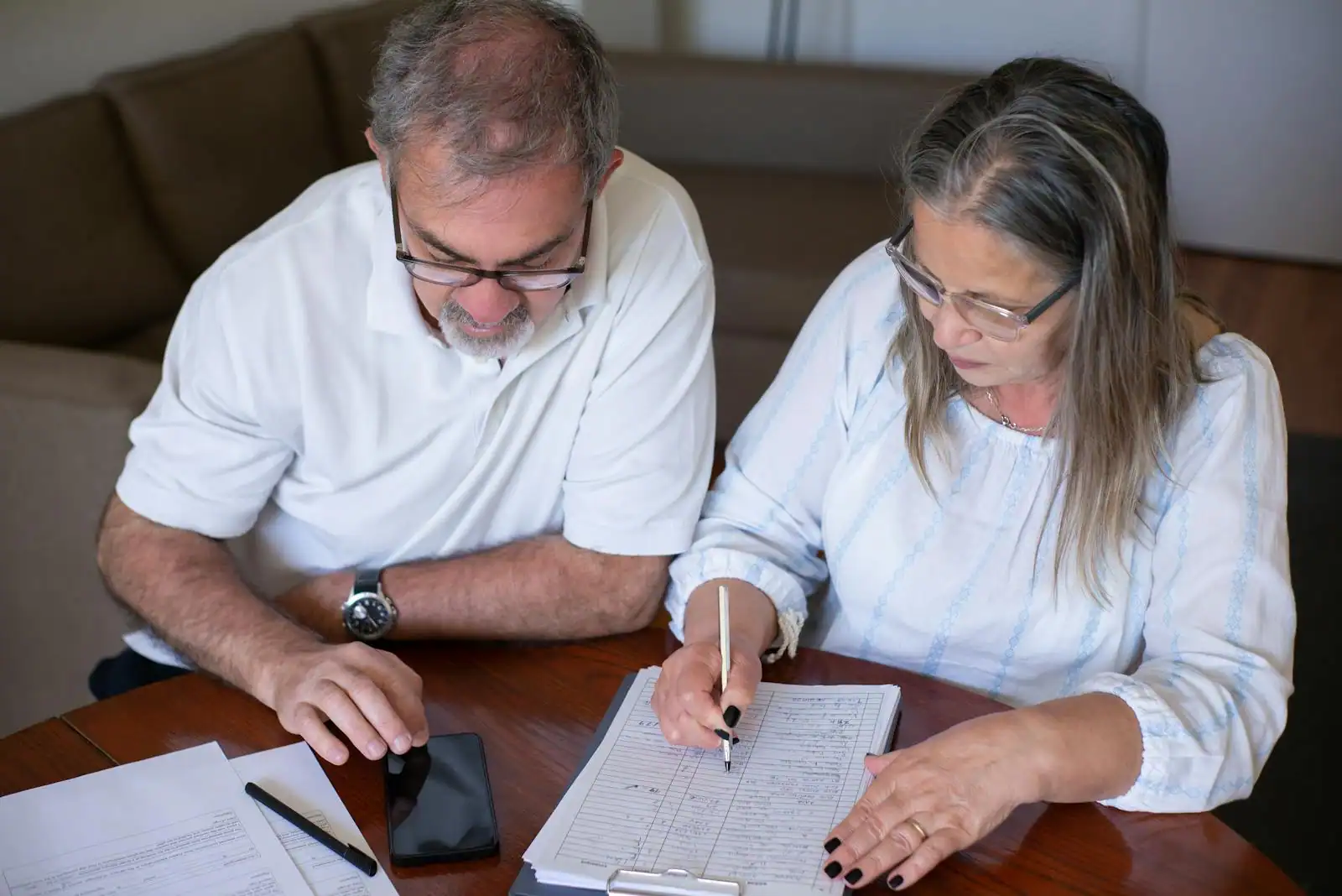 Couple consultant sereinement des documents d'épargne retraite à la table de leur salon