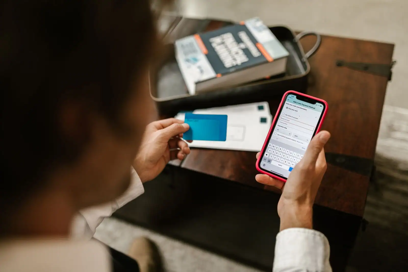 Personne gérant ses comptes sur une application bancaire, smartphone et carte en main