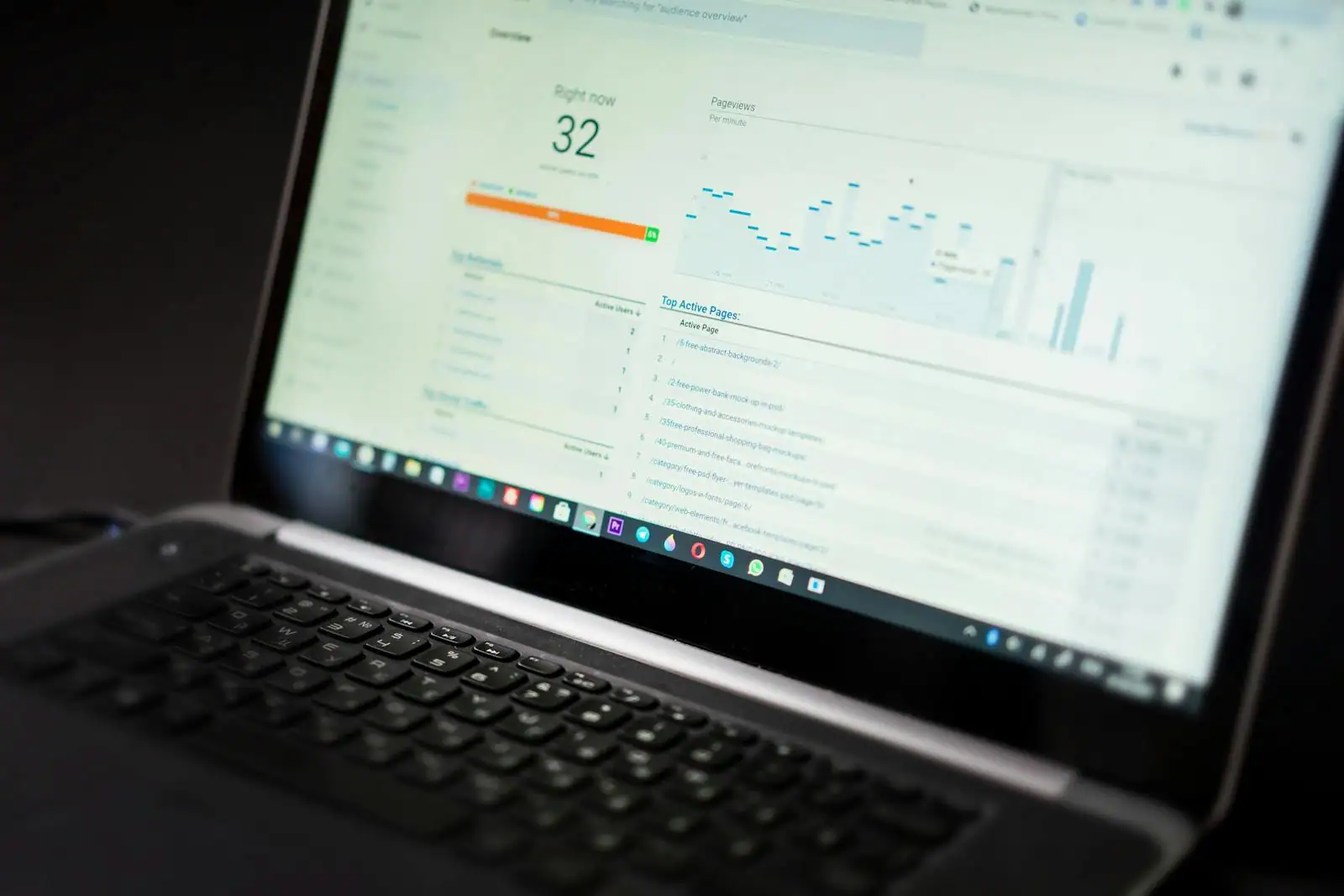 Espace de travail avec un ordinateur portable affichant des courbes d'analyse marketing, un carnet et un stylo posés à côté.