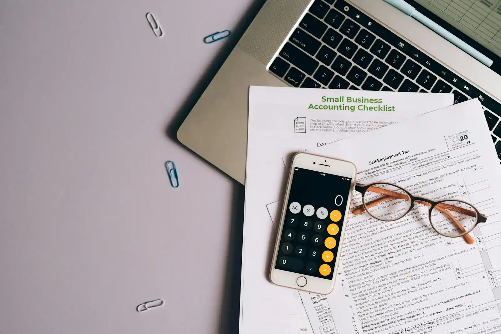 Bureau avec une déclaration de revenus papier, une calculatrice et un ordinateur portable ouvert.