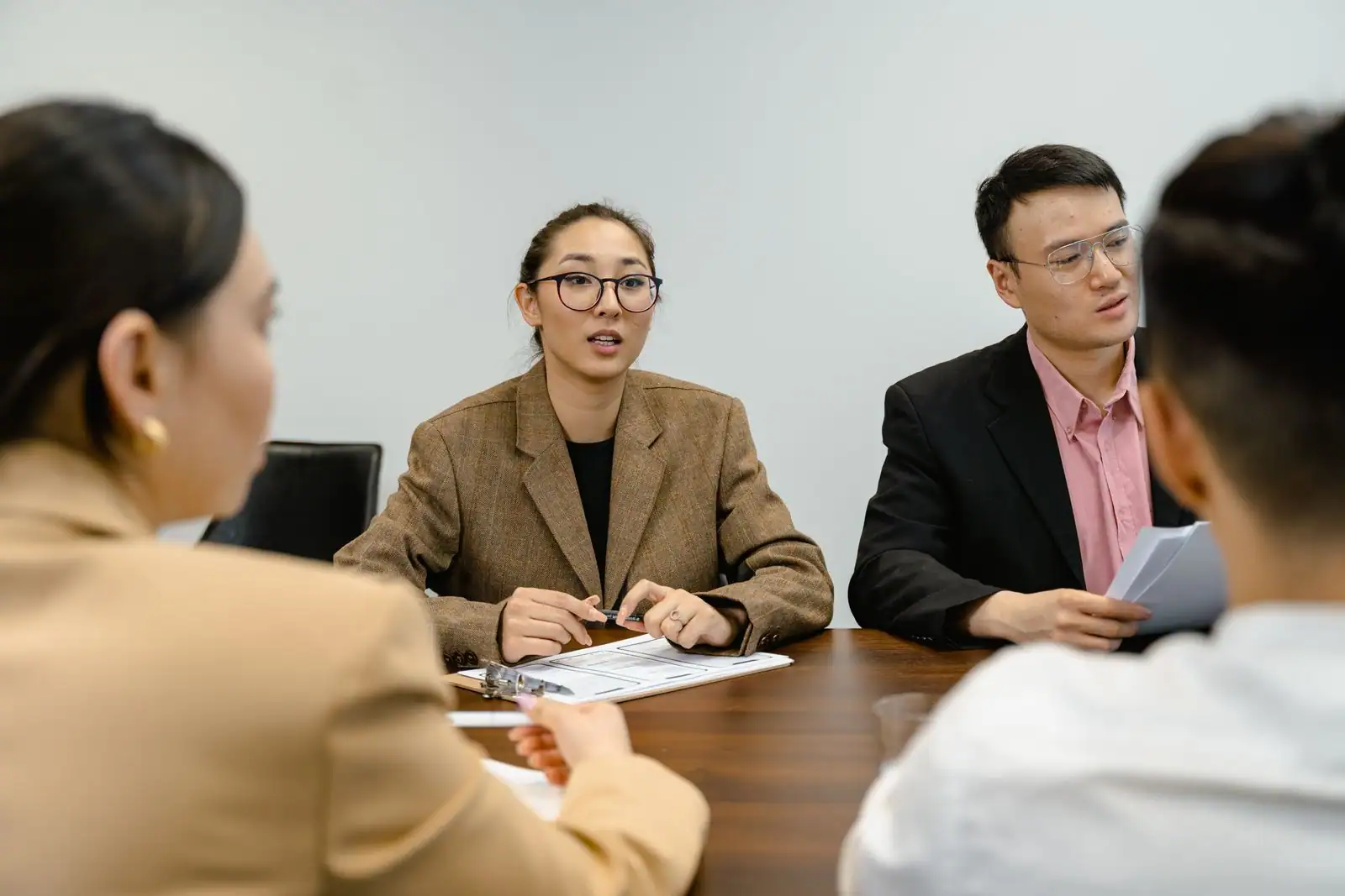 Réunion de travail en entreprise autour d'une table, plusieurs personnes en discussion.