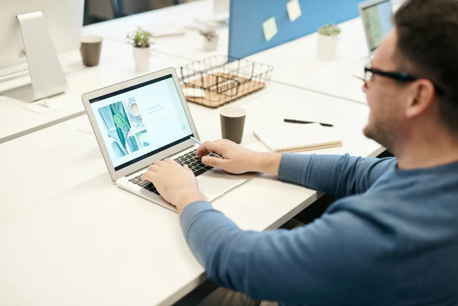 Personne consultant des offres d'emploi sur un ordinateur portable, carnet et stylo à côté