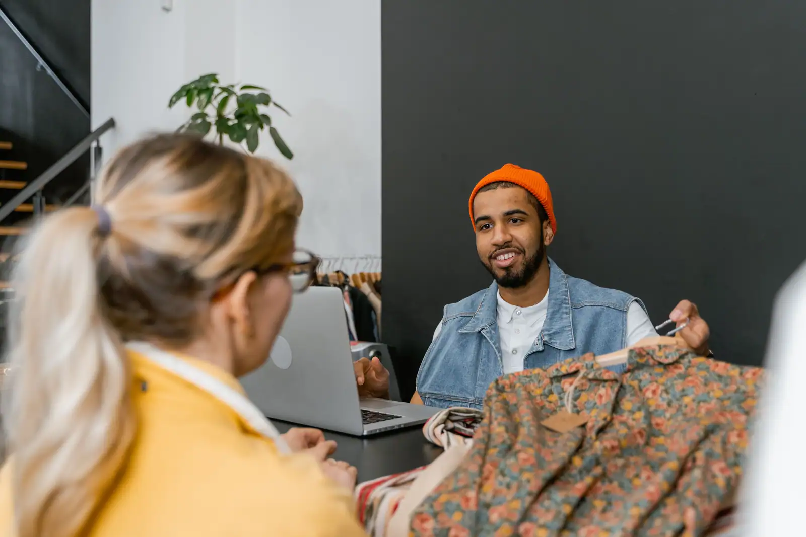 Échange au comptoir d'une boutique de vêtements : un article sur cintre est présenté à la clientèle