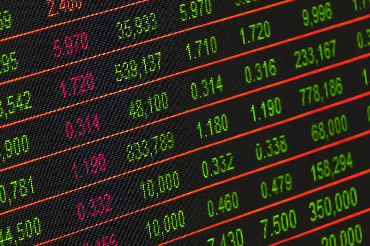 Tableau de cotation électronique affichant en vert et rouge des cours d'actions et des volumes d'échange.
