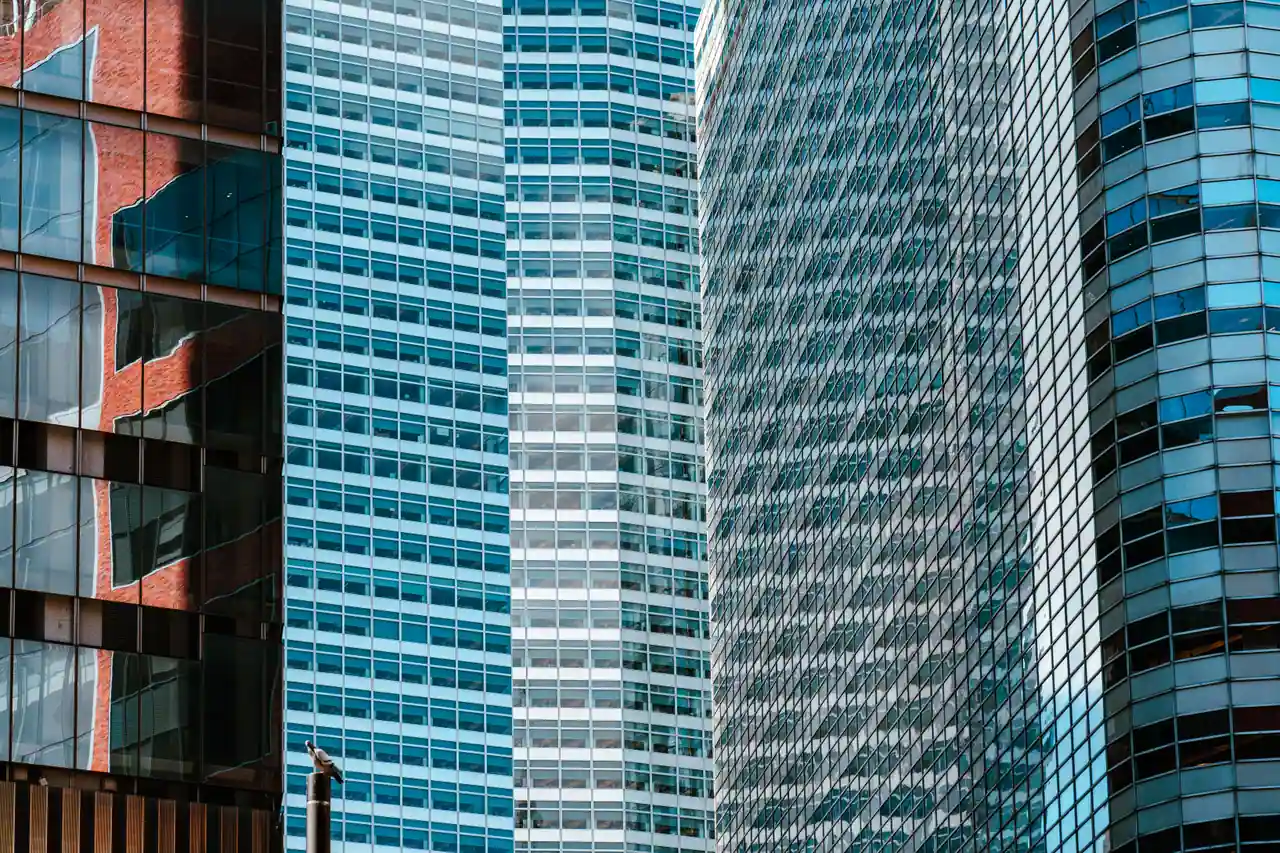 Façades vitrées de plusieurs tours de bureaux imbriquées, vues en gros plan dans un quartier d'affaires.
