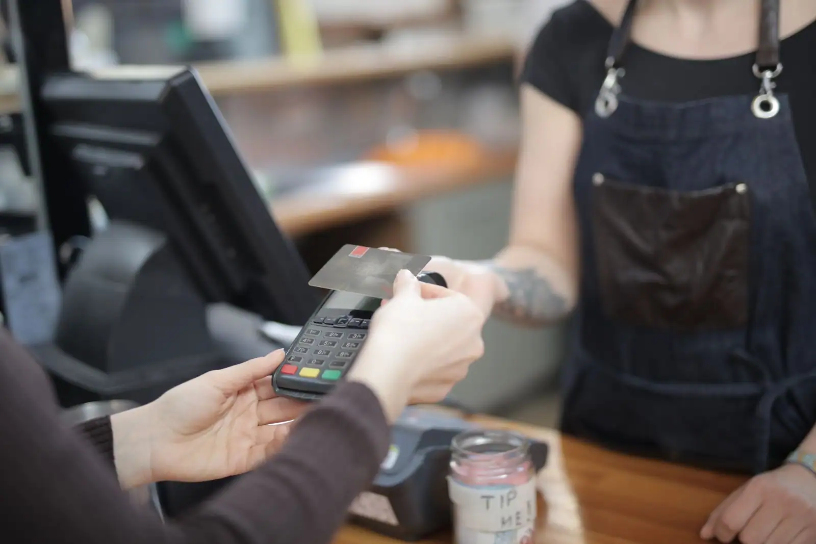 Un client règle par carte au comptoir d'un commerce de proximité, une scène quotidienne de la relation client en magasin
