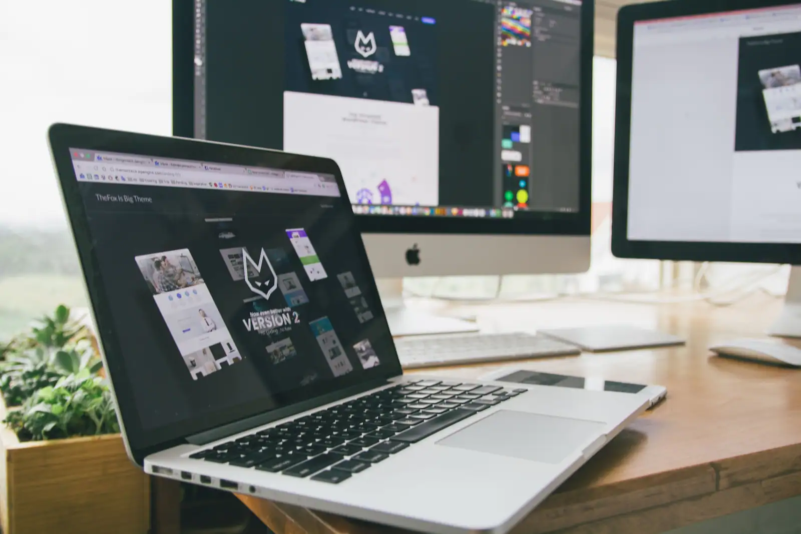 Ordinateur portable affichant la démonstration d'un thème de site web, devant deux écrans de travail