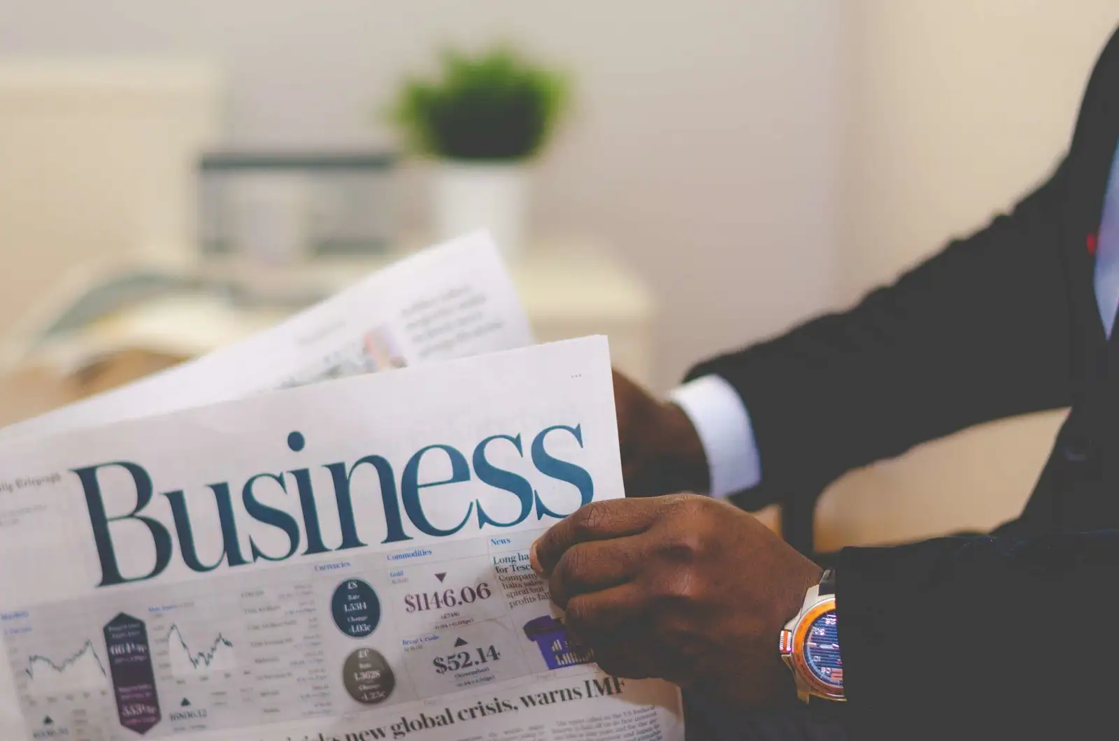 Personne lisant les pages « Business » d'un journal, illustrant la lecture attentive d'un article d'économie.