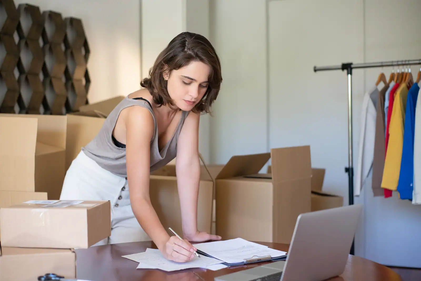 Petite entrepreneuse gérant les commandes et documents de son activité de vente en ligne.