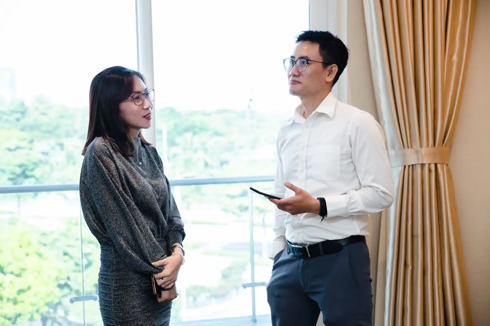 Deux collègues en conversation professionnelle, regard et posture ouverte, échange en réunion de travail.