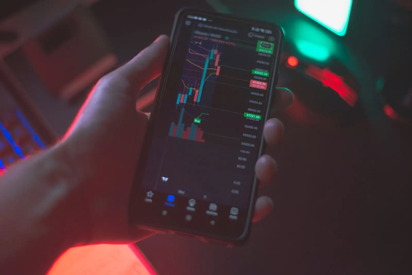 Personne consultant un graphique de cours de cryptomonnaies sur l'écran d'un smartphone.