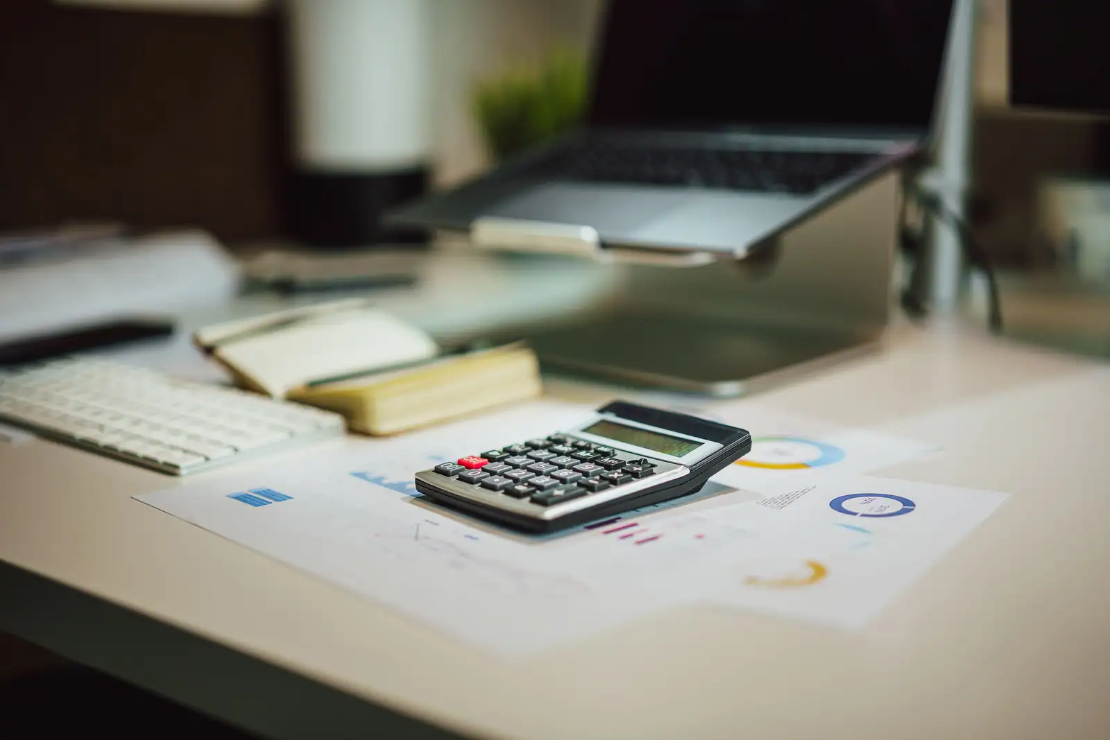 Calculatrice et graphiques financiers sur un bureau, gestion d'un compte d'épargne.