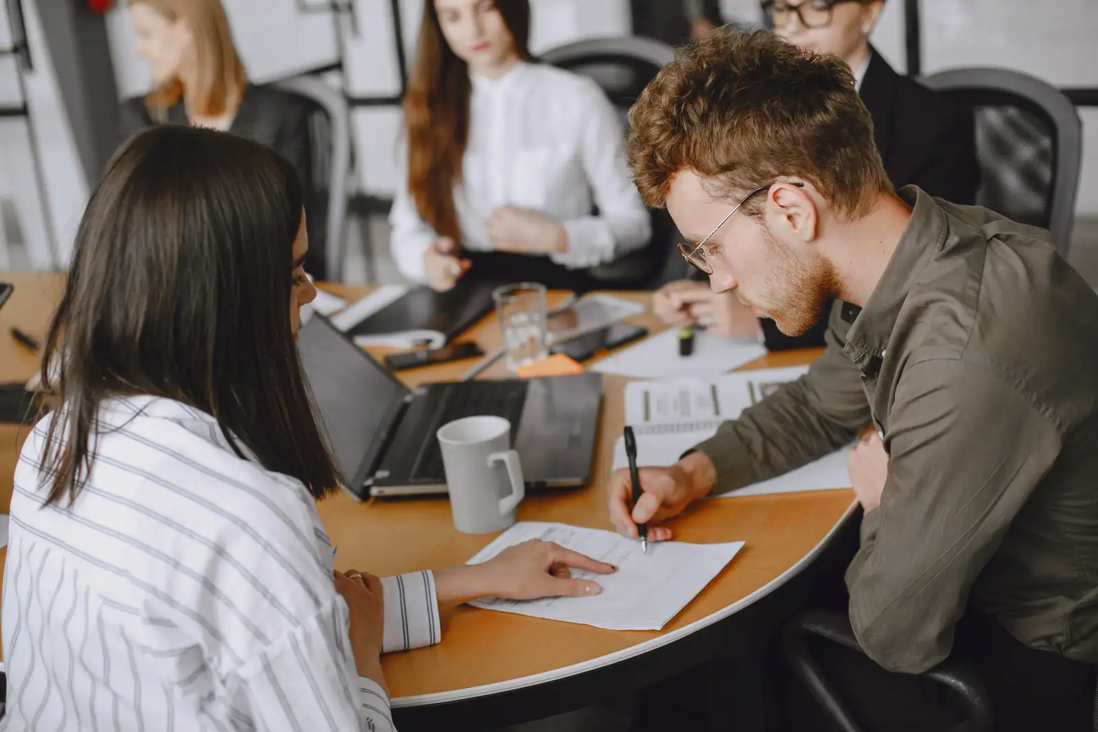 Collègues réunis autour d'une table de bureau, échangeant sur des documents de travail partagés
